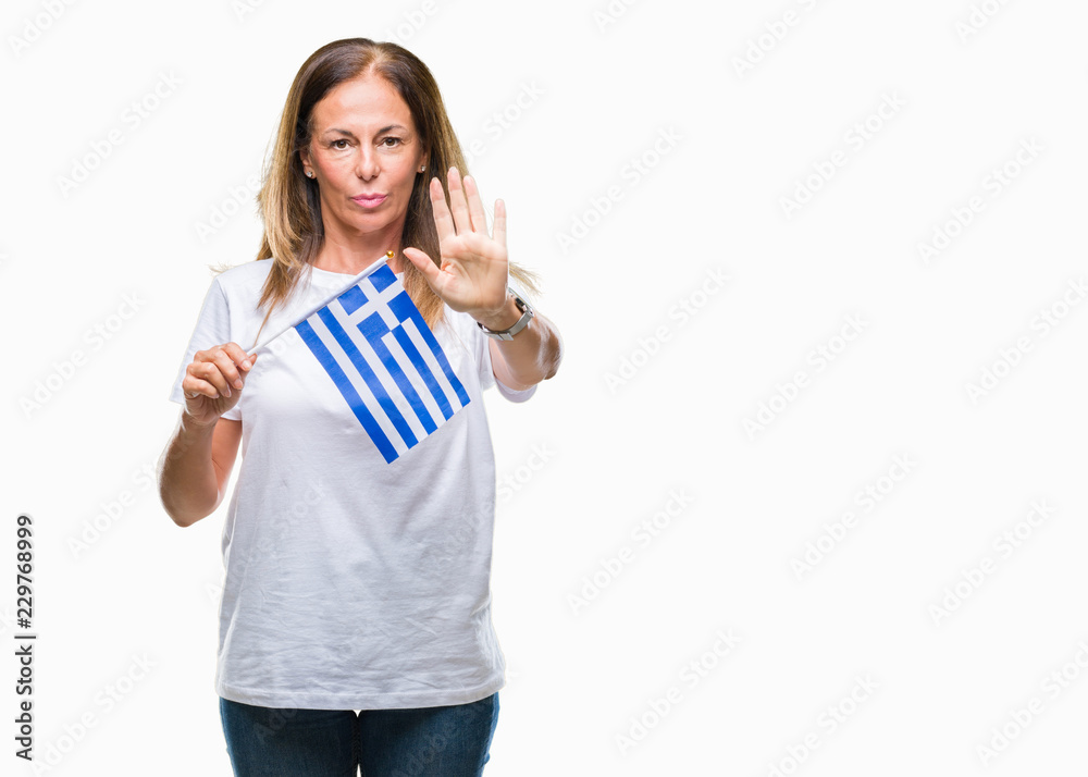 Middle age hispanic woman holding flag of Greece over isolated background with open hand doing stop sign with serious and confident expression, defense gesture Middle age hispanic woman holding flag of Greece over isolated background with open hand doing stop sign with serious and confident expression, defense gesture