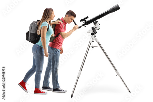 Teenage girl and boy looking through a telescope