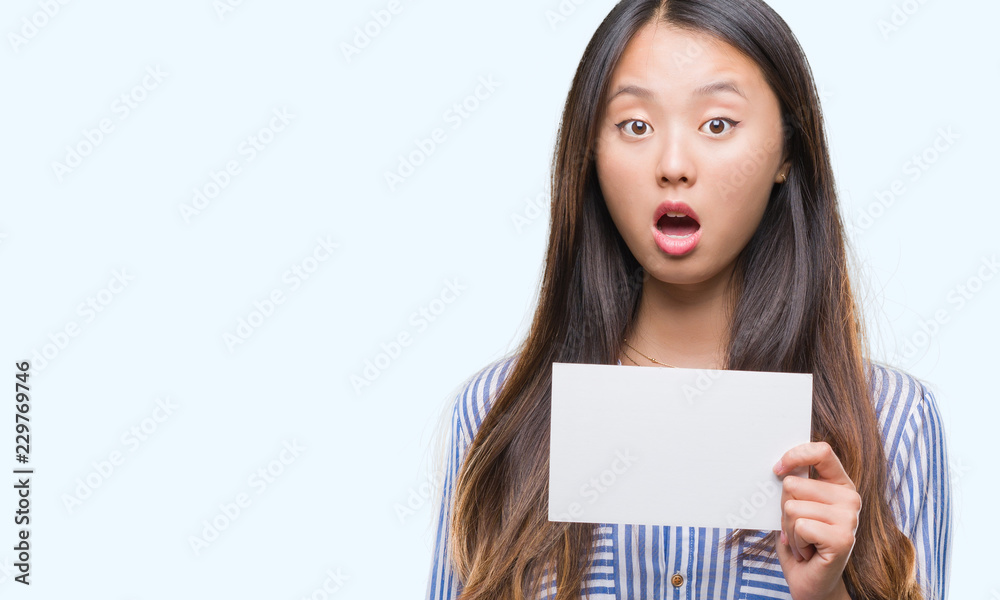 Young asian woman holding blank card over isolated background scared in shock with a surprise face, afraid and excited with fear expression Young asian woman holding blank card over isolated background scared in shock with a surprise face, afraid and excited with fear expression