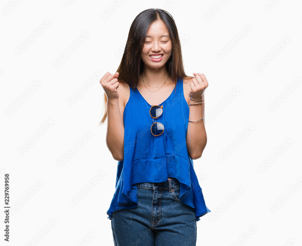 Young asian woman over isolated background excited for success with arms raised celebrating victory smiling. Winner concept. Young asian woman over isolated background excited for success with arms raised celebrating victory smiling. Winner concept.