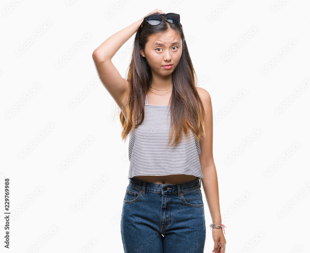 Young asian woman wearing sunglasses over isolated background confuse and wonder about question. Uncertain with doubt, thinking with hand on head. Pensive concept. Young asian woman wearing sunglasses over isolated background confuse and wonder about question. Uncertain with doubt, thinking with hand on head. Pensive concept.