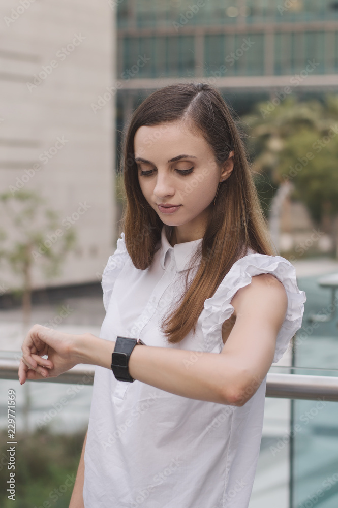 Vertical photo of young european business woman looking at her hand watches. Time management. Deadline concept. Taking a break Vertical photo of young european business woman looking at her hand watches. Time management. Deadline concept. Taking a break