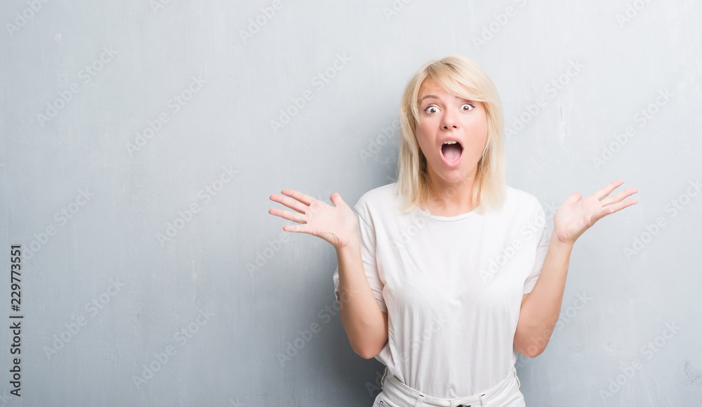 Adult caucasian woman over grunge grey wall celebrating crazy and amazed for success with arms raised and open eyes screaming excited. Winner concept Adult caucasian woman over grunge grey wall celebrating crazy and amazed for success with arms raised and open eyes screaming excited. Winner concept