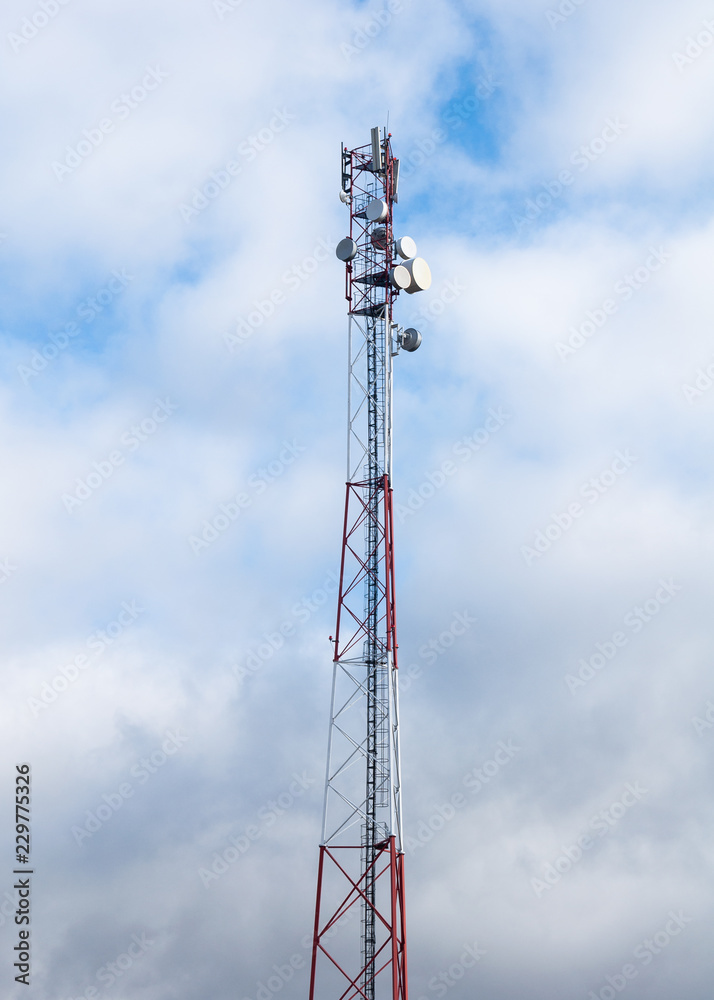 Mobile communication tower equipment on cloudy sky background