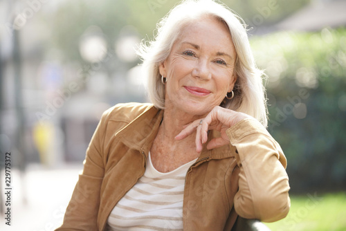 Lovely senior woman sitting on bench outdoors