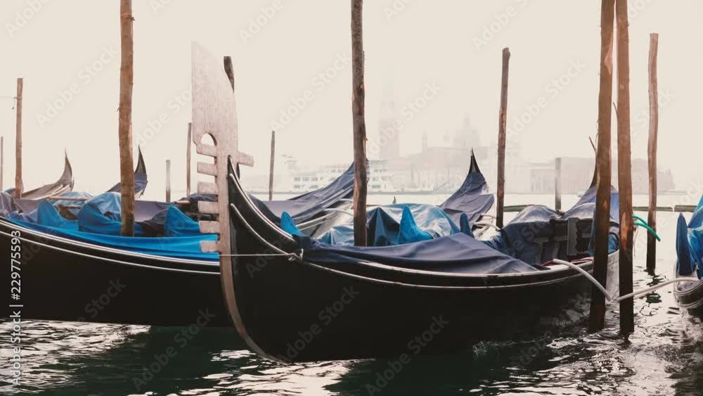 Atmospheric view of beautiful traditional gondolas rocking on the waves at foggy wooden lagoon pier in Venice, Italy. Atmospheric view of beautiful traditional gondolas rocking on the waves at foggy wooden lagoon pier in Venice, Italy.