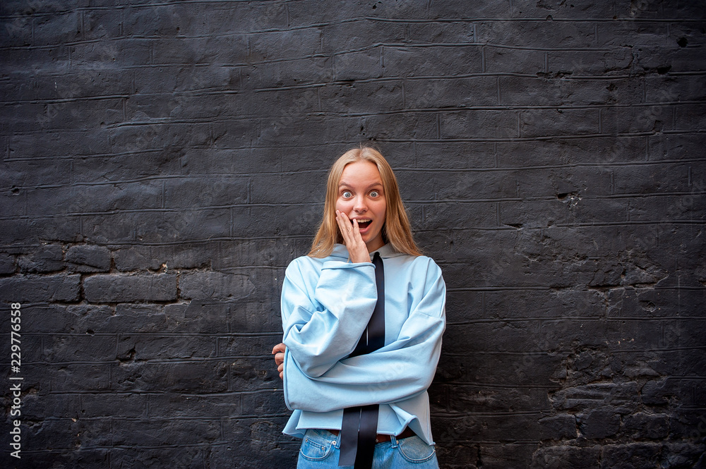 Young blonde surprised on a grey wall background