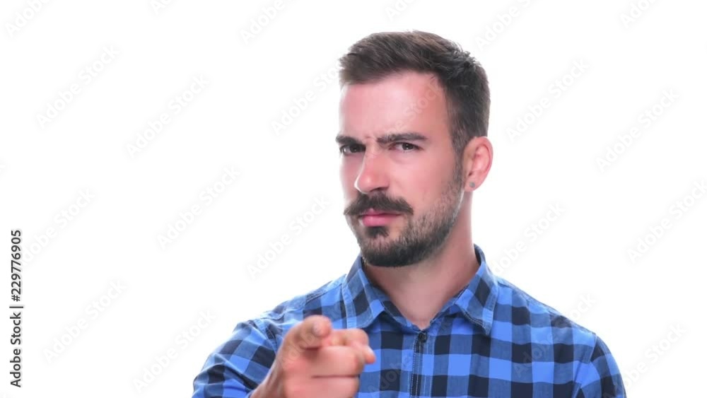 Young adult bearded man pointing at camera dissatisfied and scolding finger isolated on white background. Young adult bearded man pointing at camera dissatisfied and scolding finger isolated on white background.