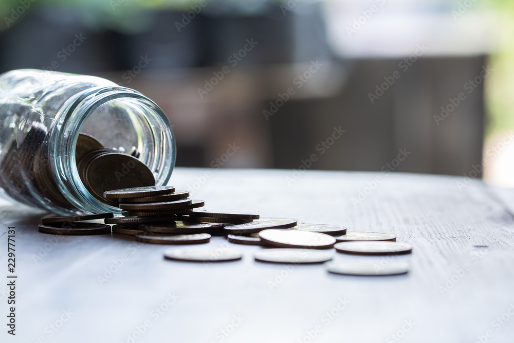 Saving money concept of collecting coins in a glass on wooden table Saving money concept of collecting coins in a glass on wooden table