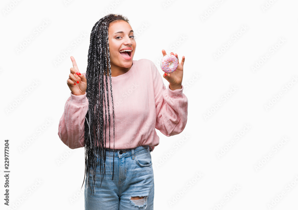 Obraz premium Young african american girl eating pink donut over isolated background surprised with an idea or question pointing finger with happy face, number one