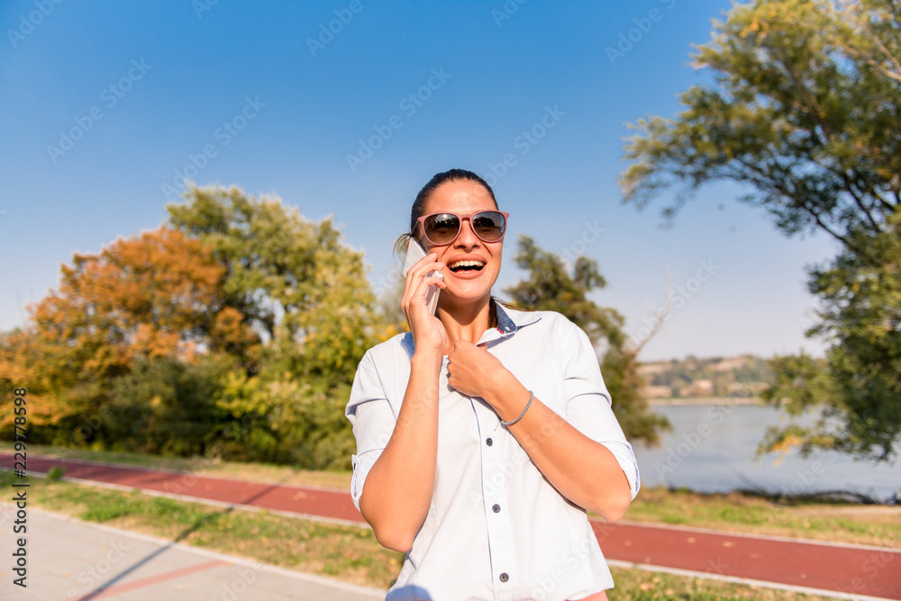 Young woman using mobile phone in the park by river Young woman using mobile phone in the park by river