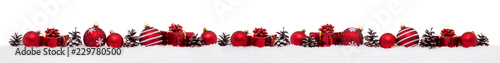 Row of red christmas baubles with xmas present gift boxes isolated on snow
