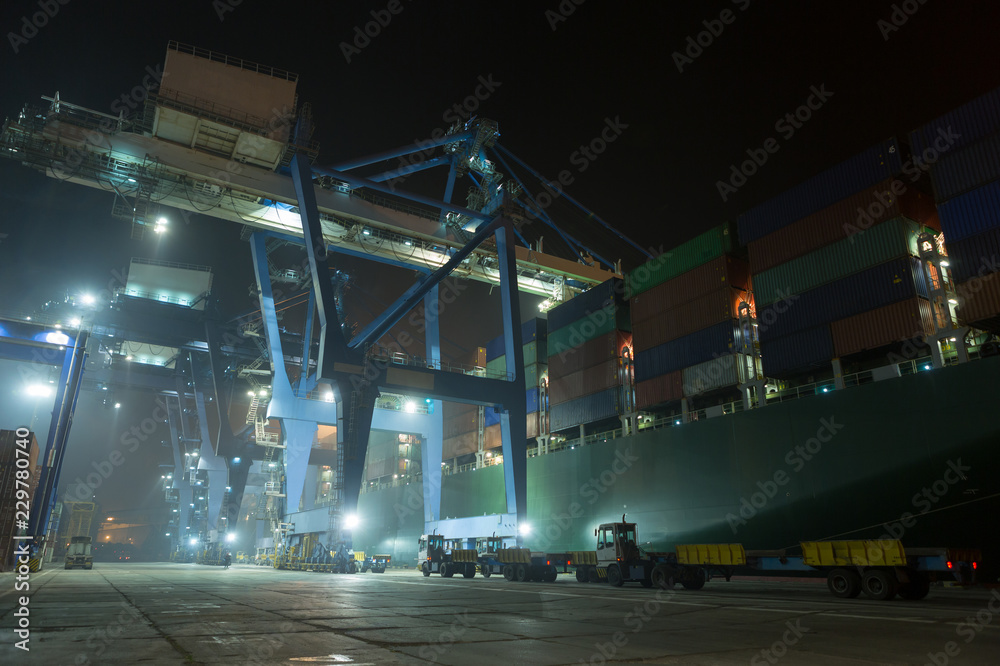 Container ship in port at container terminal in night. container ships stand in terminal of port on loading, unloading container. Sea port Cotnainer terminal.