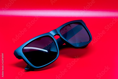 Fashion sunglasses isolated on red background, black plastic.