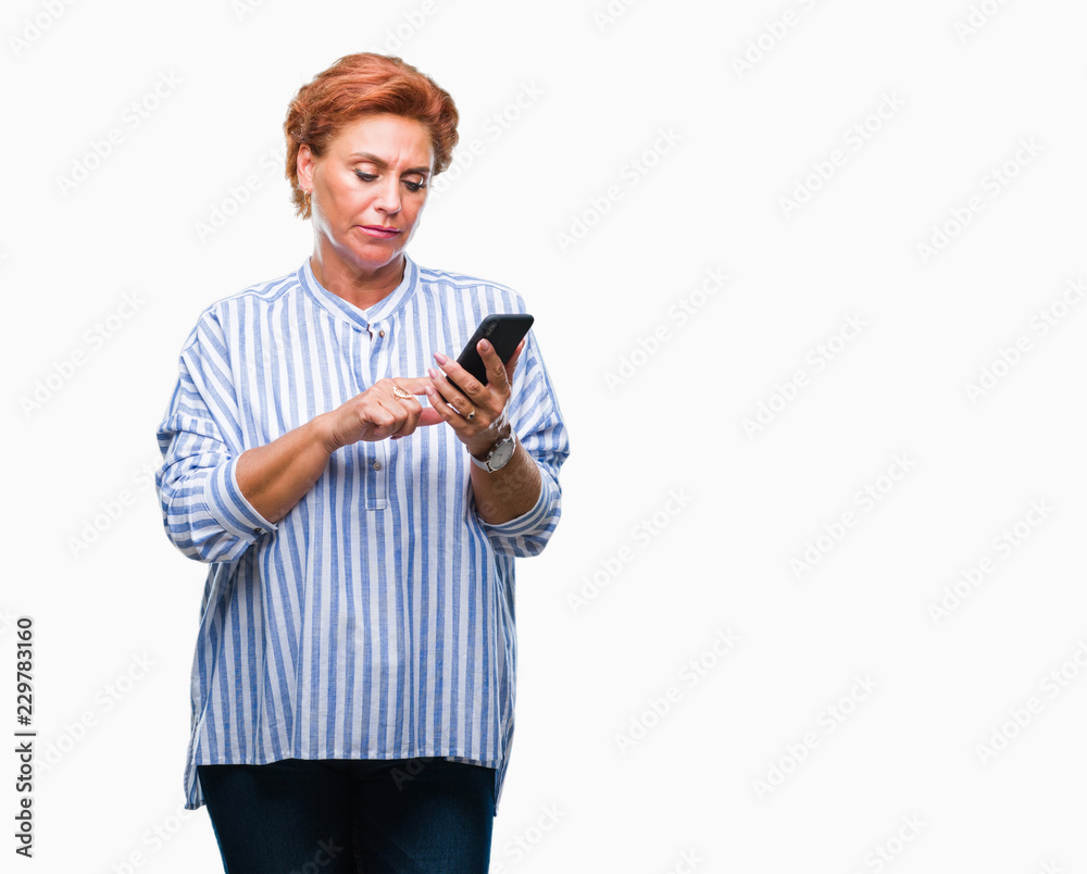 Atrractive senior caucasian redhead woman texting using smartphone over isolated background with a confident expression on smart face thinking serious Atrractive senior caucasian redhead woman texting using smartphone over isolated background with a confident expression on smart face thinking serious