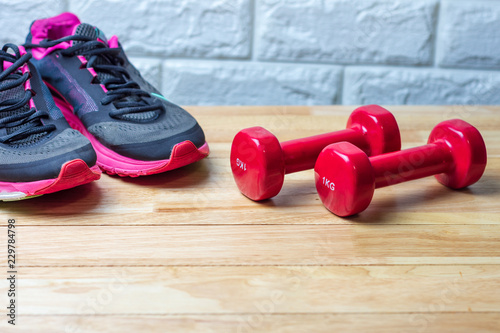 Dumbbells and sport shoes on wooden floor, fitness concept