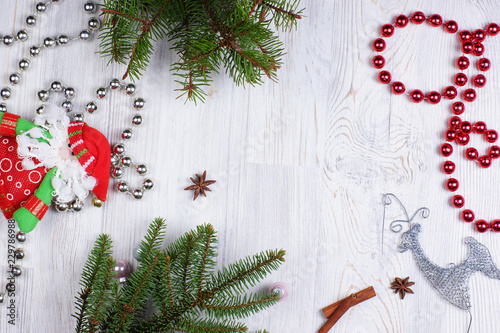 Brilliant beads, Christmas tree, toy Santa Claus and deer, as well as cinnamon sticks and anise stars on a wooden light background. photo