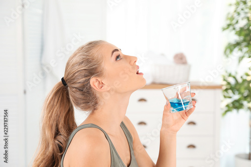 Woman rinsing mouth with mouthwash in bathroom. Teeth care