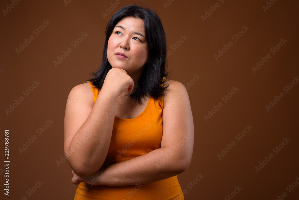 Obraz premium Beautiful overweight Asian woman thinking and looking up