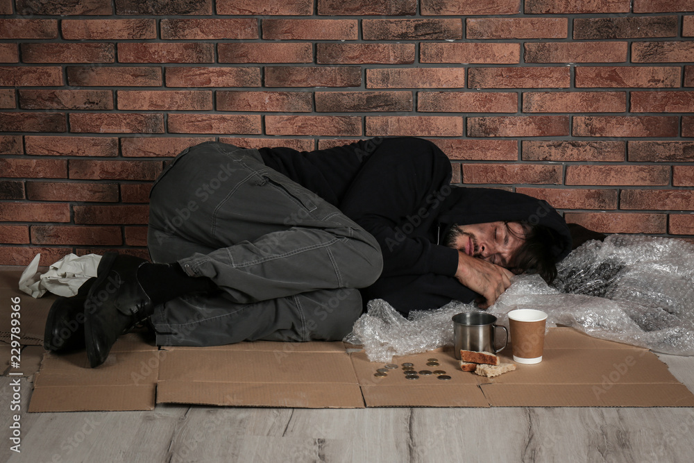 Poor man sleeping on floor near brick wall Poor man sleeping on floor near brick wall