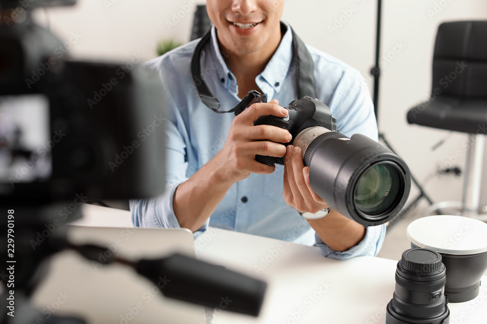 Male photo blogger recording video on camera indoors