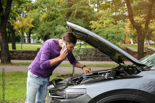 Man talking on phone near broken car outdoors photo