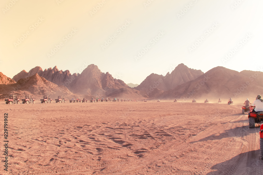 Naklejka premium Desert in Egypt. Sharm el Sheikh. Sand and Sand Borkhan. Rock and sunset. Quad Cycle Travel. Excursion with people.