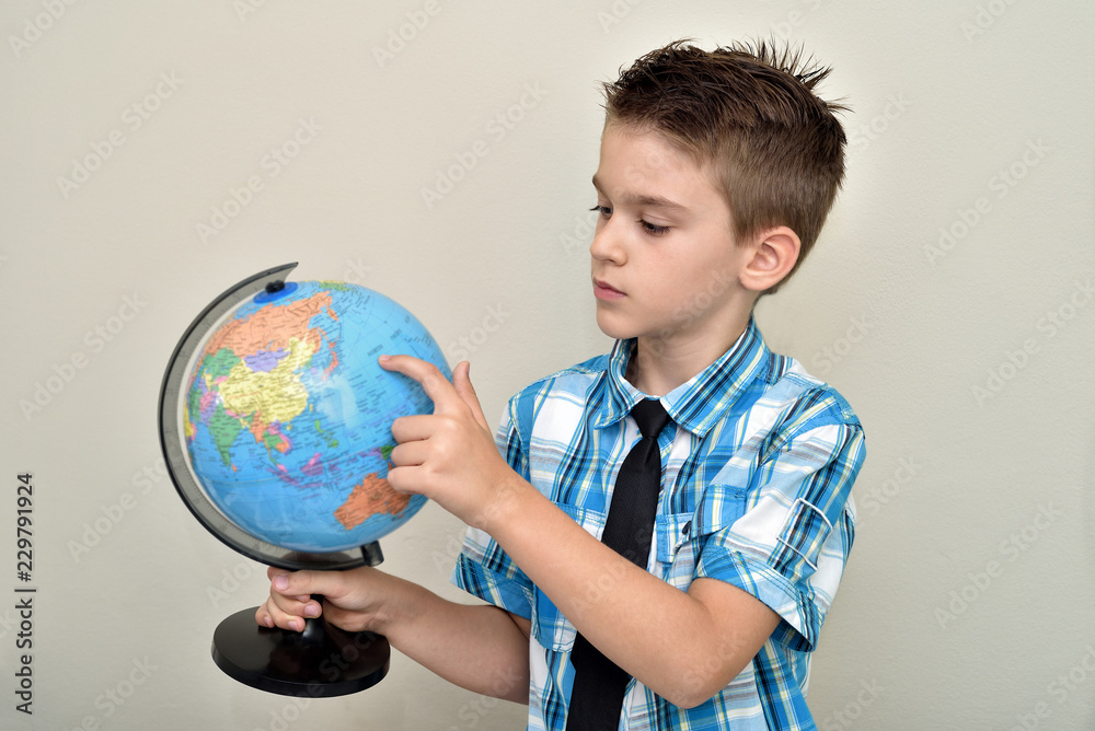 Cute young boy holding, looking at and examining the globe. Focus on the young boy. Cute young boy holding, looking at and examining the globe. Focus on the young boy.