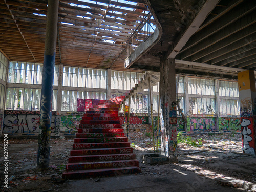 Stairs leading up to another floor in an old abandoned building or factory, completely destroyed and vandalized, painted with colourful graffiti street art