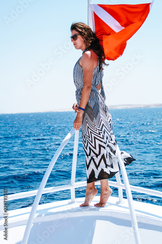 The girl in a black and white dress in a geometric strip. Dissolved hair. Journey on boat on the red sea in Egypt. Brunette on the trip. Fashion photo shoot