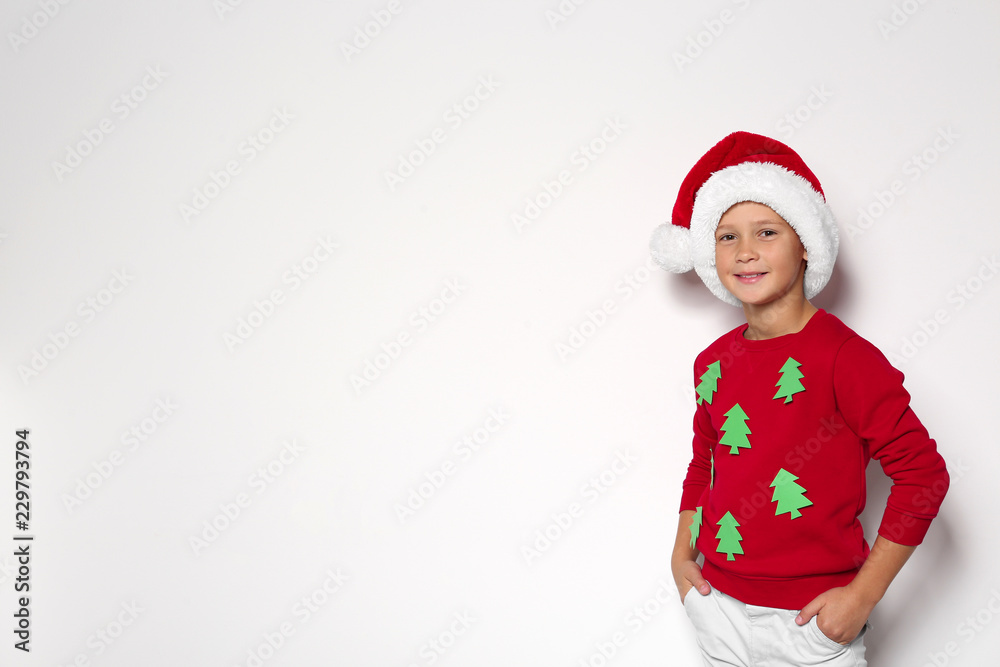 Cute little boy in handmade Christmas sweater and hat on white background. Space for text Cute little boy in handmade Christmas sweater and hat on white background. Space for text