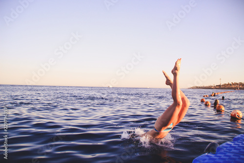 The girl in a blue bikini dives into the water. Leap in the red sea in Egypt. Red-haired woman Water splashes.