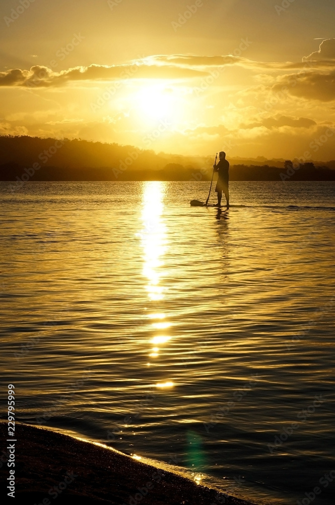  man practicing stand up paddle on the lagoon at sunset                              
