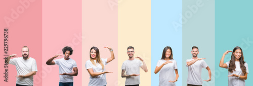 Collage of different ethnics young people wearing white t-shirt over colorful isolated background gesturing with hands showing big and large size sign  measure symbol. Smiling looking at the camera