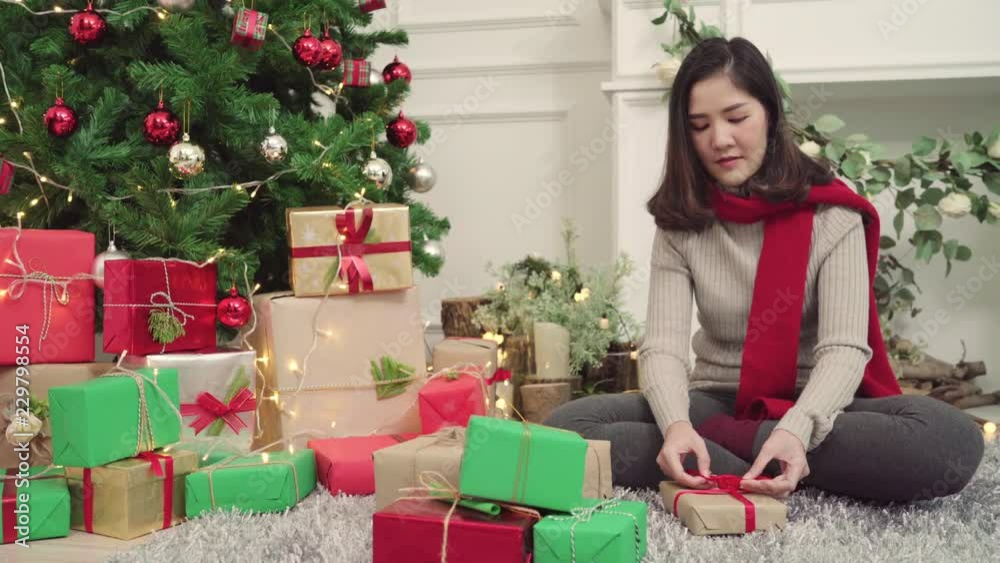 Cheerful happy young Asian woman packing and wrapping Christmas present decorate her living room at home in Christmas Festival. Lifestyle woman celebrate Christmas and New year concept. Cheerful happy young Asian woman packing and wrapping Christmas present decorate her living room at home in Christmas Festival. Lifestyle woman celebrate Christmas and New year concept.