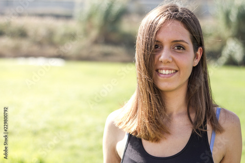 sportswoman girl smiling after doing sport dressed in black near a green meadow