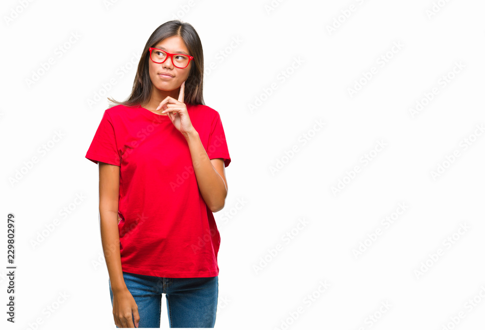 Young asian woman wearing glasses over isolated background with hand on chin thinking about question, pensive expression. Smiling with thoughtful face. Doubt concept. Young asian woman wearing glasses over isolated background with hand on chin thinking about question, pensive expression. Smiling with thoughtful face. Doubt concept.