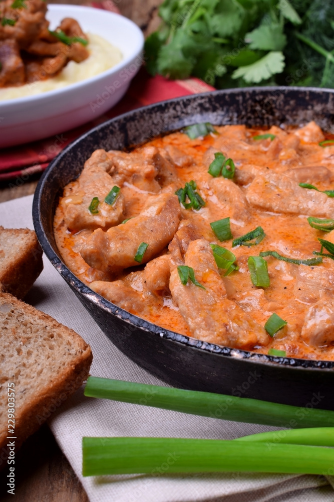Pieces of meat stewed in tomato and sour cream sauce in the frying pan Pieces of meat stewed in tomato and sour cream sauce in the frying pan