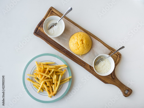 Romanian corn porridge Mamalyga with cheese and sour cream and french potatoes on a wooden stand. photo