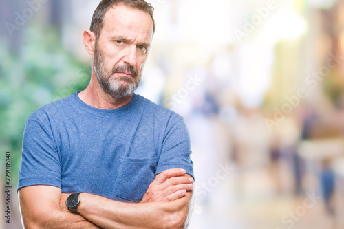 Middle age hoary senior man over isolated background skeptic and nervous, disapproving expression on face with crossed arms. Negative person.