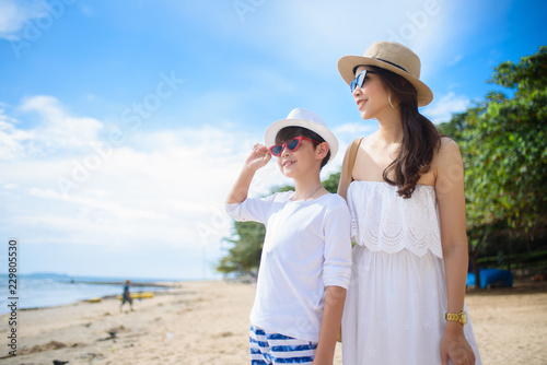  happy family mother with boy walks holding hand on the beach ,white sand beach  ,look happy in the summer © Krongsak