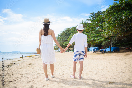  happy family mother with boy walks holding hand on the beach ,white sand beach  ,look happy in the summer