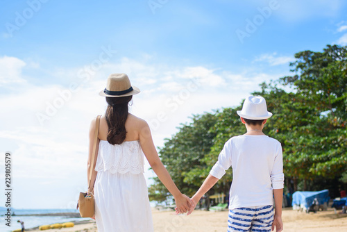  happy family mother with boy walks holding hand on the beach ,white sand beach  ,look happy in the summer