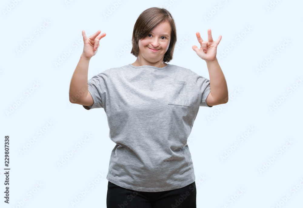 Young adult woman with down syndrome over isolated background shouting with crazy expression doing rock symbol with hands up. Music star. Heavy concept. Young adult woman with down syndrome over isolated background shouting with crazy expression doing rock symbol with hands up. Music star. Heavy concept.