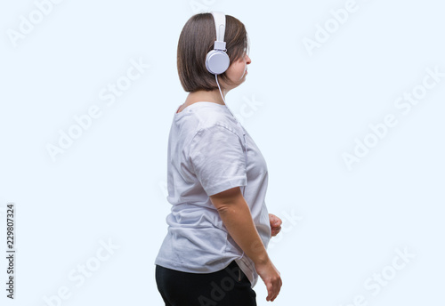 Young adult woman with down syndrome wearing headphones over isolated background looking to side, relax profile pose with natural face with confident smile.