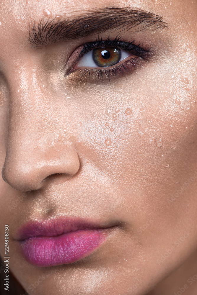 Naklejka premium Close up gamour beauty woman portrait. Fashion wet shiny skin, with drops sexy gloss lips make-up and pink eyebrows