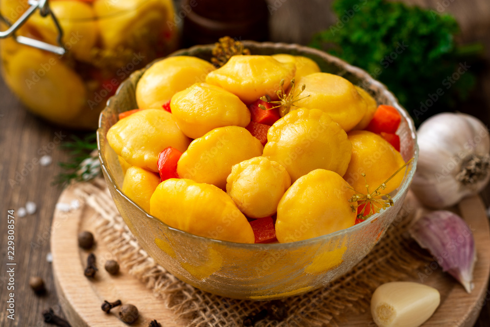 Marinated pattypan squash in glass bowl on dark rustic wooden background. Selective focus. Marinated pattypan squash in glass bowl on dark rustic wooden background. Selective focus.