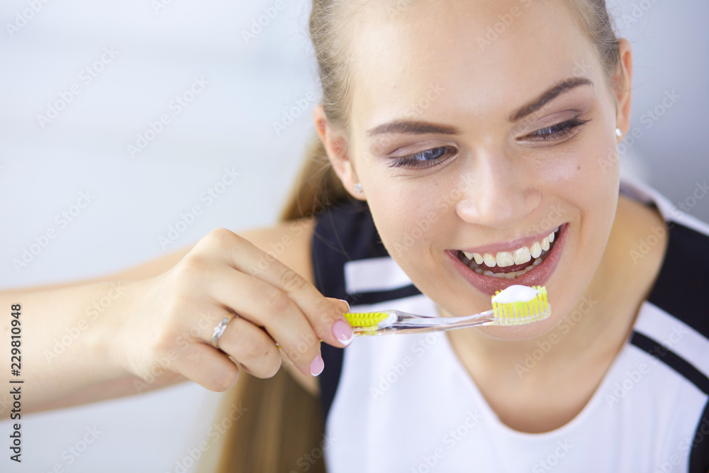 Smiling young woman with healthy teeth brushing her teeth Smiling young woman with healthy teeth brushing her teeth