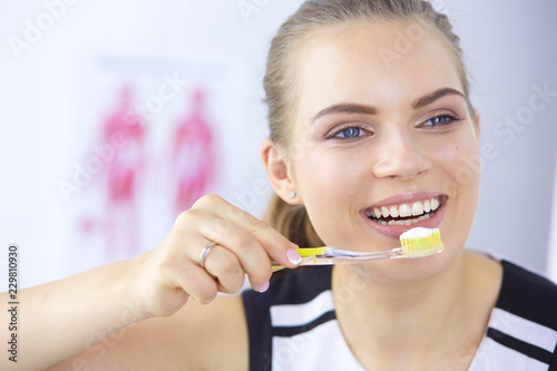 Smiling young woman with healthy teeth brushing her teeth
