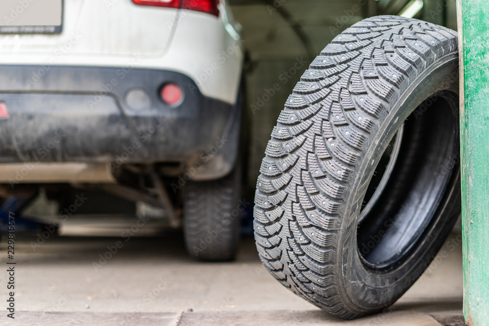 car mechanic screwing or unscrewing car wheel of lifted automobile at repair service station car mechanic screwing or unscrewing car wheel of lifted automobile at repair service station